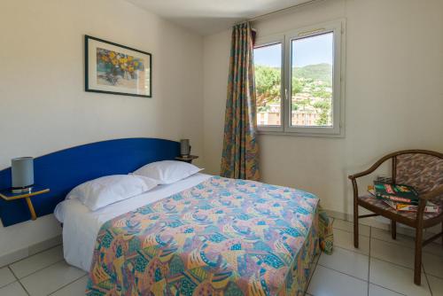 - une chambre avec un lit, une fenêtre et une chaise dans l'établissement Lagrange Vacances Villa Barbara, à Cavalaire-sur-Mer