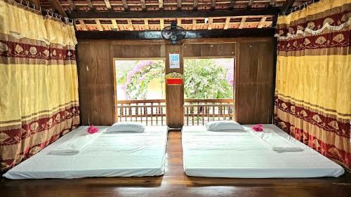twee bedden in een kamer met een raam bij Homestay Chung Thúy in Ha Giang