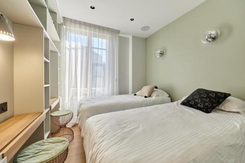 deux lits dans une chambre avec une fenêtre dans l'établissement Morny Haven - A 500m de la plage, à Deauville