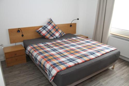 Dormitorio con cama con edredón de cuadros y almohada en FeWo Oda, en Bad Gandersheim