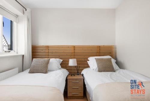 dwa łóżka w małej sypialni z zagłówkiem w obiekcie OnSiteStays - EARLY CHECK IN MAY - Modern 3 bed House, 2 x Parking, Garden, WIFI & dishwasher w mieście Bromley