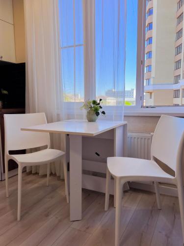 a white table and chairs in a room with windows at Эко студия Вокзал Харьков-Пассажирский in Kharkiv