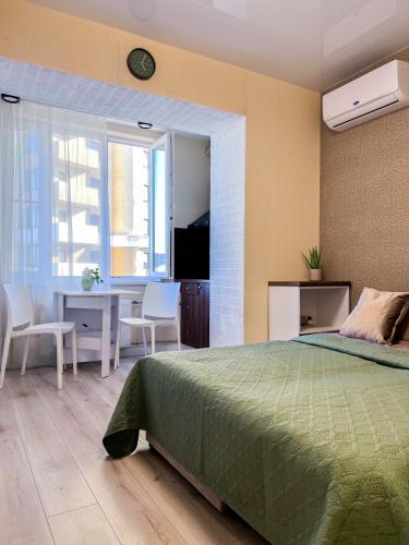 a bedroom with a green bed and a table and chairs at Эко студия Вокзал Харьков-Пассажирский in Kharkiv