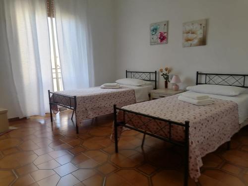 een kamer met twee bedden en twee tafels erin bij Le stanze della villa in Sambuca di Sicilia