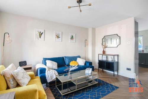 a living room with a blue couch and a table at OnSiteStays - EARLY CHECK IN AUGUST - Modern 3 bed House, 2 x Parking, Garden, WIFI & dishwasher in Bromley