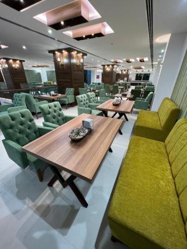 a dining room with a wooden table and green chairs at Hotel Classy Stay in Erbil