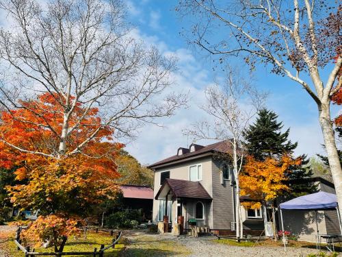 una casa en otoño con árboles en 民泊JOYFUL天然温泉付きログハウス, en Shiraoi