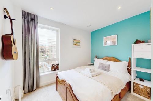 a bedroom with a bed with a blue accent wall at Modern and spacious 4 bed house in the city centre in London
