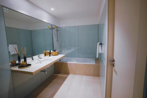 un bagno con vasca, lavandino e specchio di Funchal Centrum Apartment a Funchal