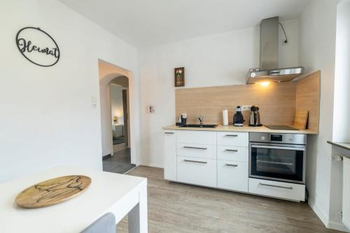 a kitchen with white cabinets and a white table at FerienwohnungHeimatgefühl in Rimpar