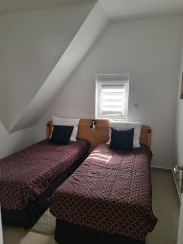 two beds in a attic room with a window at Luxe et Détente Près du Luxembourg 