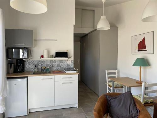 - une cuisine avec des placards blancs et une table avec un voilier dans l'établissement Studio au calme avec jardin et stationnement, à Vannes