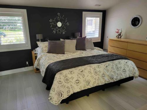 1 dormitorio con 1 cama grande y pared negra en Anthropocene Jewel Cottage, en Milton