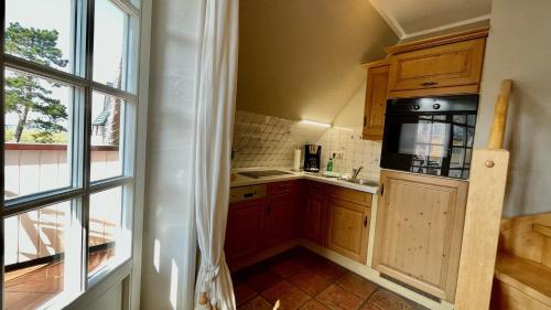 a small kitchen with wooden cabinets and a window at Haus Strandgut FW 4 in Ahrenshoop