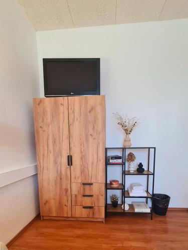a wooden cabinet with a flat screen tv on a wall at Horn Gästehaus in Leinfelden-Echterdingen