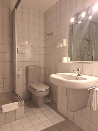 a white bathroom with a sink and a toilet at Hotel Union in Offenburg