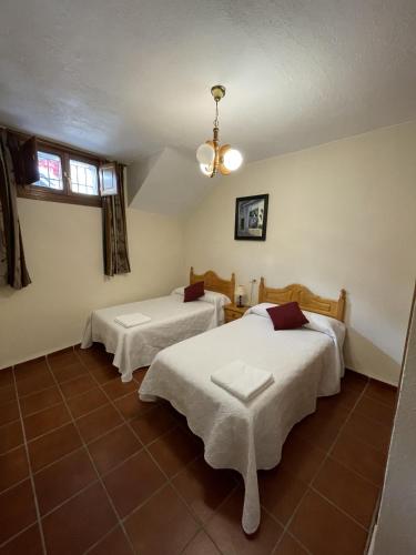 a bedroom with two beds and a chandelier at Apartamentos Rurales Las Chimeneas in Capileira