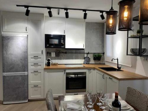 una cocina con armarios blancos y una mesa con sillas. en Apartamento El Rinconzuelo, en Rubielos de Mora