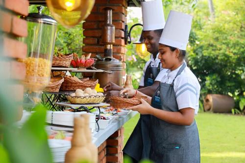 un uomo e una donna con cappelli da chef che preparano il cibo di Wisdom Boutique Resort a Kandy