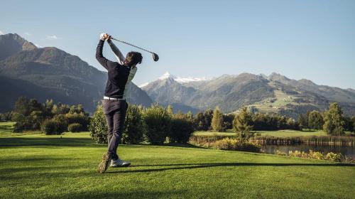 a man swinging a golf club on a golf course at Lakeside Luxury Apartments in Zell am See