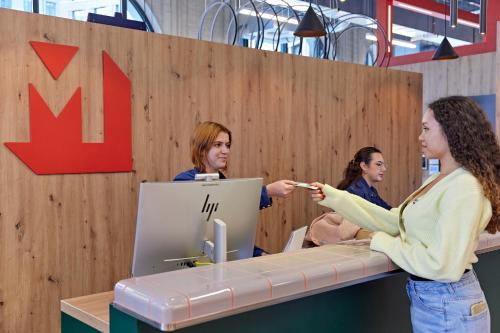 two women standing at a counter in an office at MEININGER Hotel Köln West in Cologne