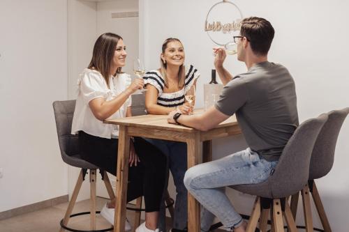 a group of three people sitting at a table with wine glasses at Grenzblick in Eisenberg an der Pinka