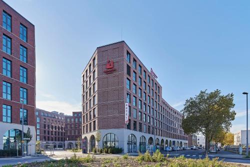 a tall brick building on a city street at MEININGER Hotel Köln West in Cologne