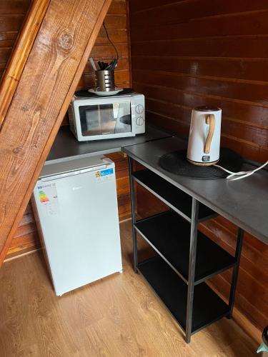 a small kitchen with a microwave and a refrigerator at CABANĀ TIP A LA 300 m De CASTEL in Hunedoara