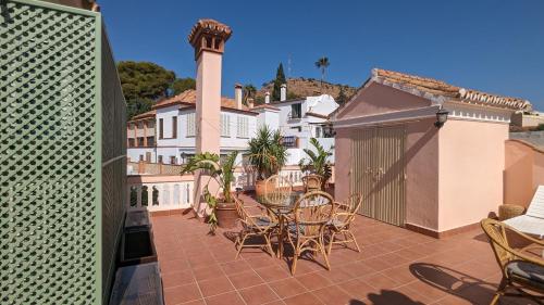 eine Terrasse mit Stühlen, einem Tisch und einem Gebäude in der Unterkunft Casa Monte Victoria in Málaga