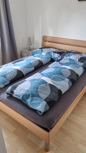 a bed with a blue and black comforter on it at La joyeuse étape in Sonceboz