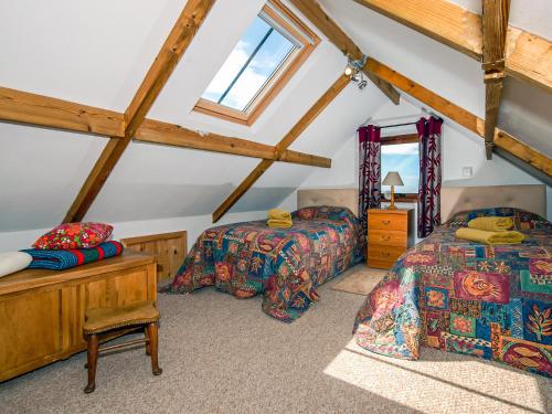 a attic bedroom with two beds and a window at Beacon Cottage in Llanrian