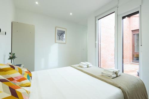 ein weißes Schlafzimmer mit einem Bett und einem Fenster in der Unterkunft INSIDEHOME Apartments - La Casita de Álex in Palencia