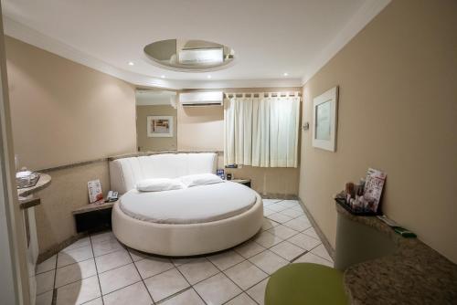 um quarto com uma grande cama branca num quarto em Motel Scala em Salvador