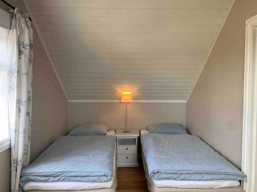 two beds in a small room with a window at Mølleråsen Apartment in Sandefjord