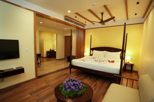 um quarto de hotel com uma cama e uma televisão em Misty Queen By Dimora Hotels em Kakkadampoyil