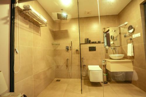uma casa de banho com um chuveiro, um WC e um lavatório. em Misty Queen By Dimora Hotels em Kakkadampoyil