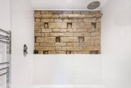 a bathroom with a brick wall and a shower at The Dovecote - Collins Farm in Bristol