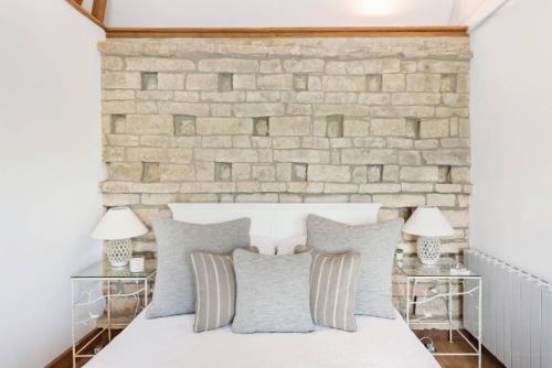 a bedroom with a brick wall and a bed with pillows at The Dovecote - Collins Farm in Bristol