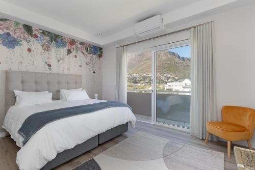 豪特湾Beach House Hout Bay的一间带床、窗户和椅子的卧室