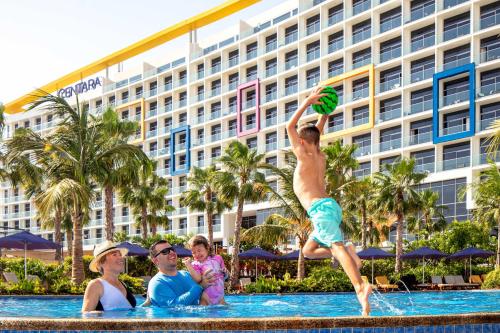 a man jumping into a swimming pool with a frisbee at Centara Mirage Beach Resort Dubai in Dubai