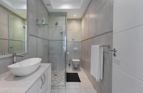 een badkamer met een wastafel, een toilet en een douche bij Beach House Hout Bay in Hout Baai