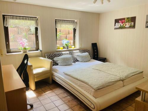 ein Schlafzimmer mit einem Bett und einem Stuhl sowie zwei Fenstern in der Unterkunft Privatunterkunft mit Bad und Küche in Seenähe in Zülpich
