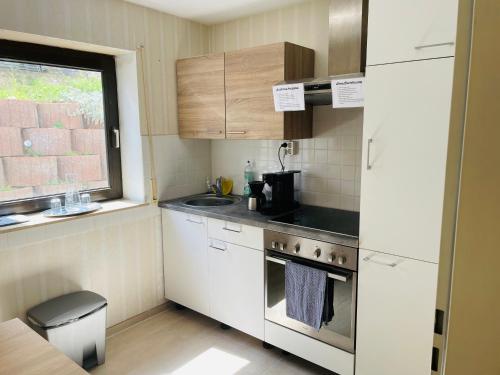 eine kleine Küche mit weißen Geräten und einem Fenster in der Unterkunft Privatunterkunft mit Bad und Küche in Seenähe in Zülpich