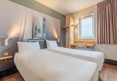 コルマールにあるB&B HOTEL Colmar Vignobles Ouestのベッド2台とデスクが備わるホテルルームです。