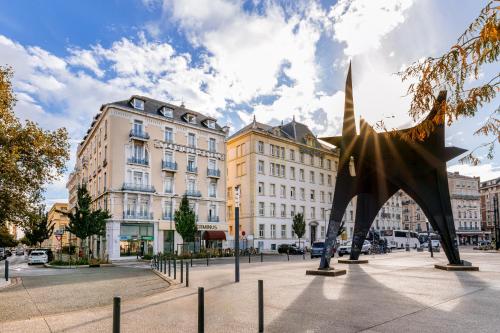 a statue in the middle of a city with buildings at Hôtel Terminus in Grenoble