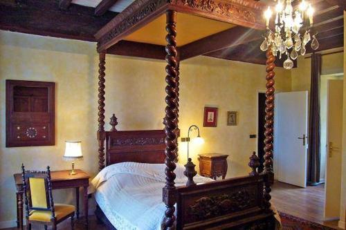 パンポンにあるMANOIR DU TERTRE au coeur de la forêt de Brocéliandeのベッドルーム(天蓋付きベッド1台、テーブル、椅子付)