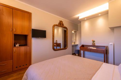 a bedroom with a bed and a mirror and a dresser at Finday Eco Boutique Hotel in Kalavrita