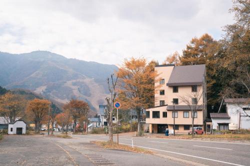 an empty street with a house and a mountain at 豊島ロッヂ苗場 in Yuzawa