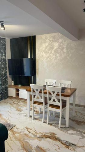 ein Esszimmer mit einem Tisch, Stühlen und einem TV in der Unterkunft Apartament Zielony 12/2 in Starogard Gdański
