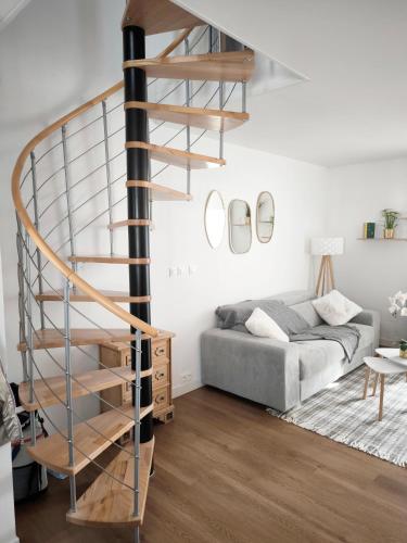 - un escalier en colimaçon dans le salon doté d'un canapé dans l'établissement Charmante maison proche de la mer, à Saint-Pol-de-Léon